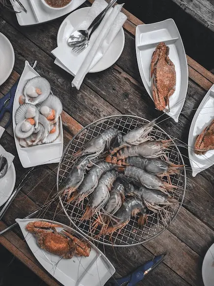 Marisco (gambas, pescado, ostras) servido en platos sobre una mesa.