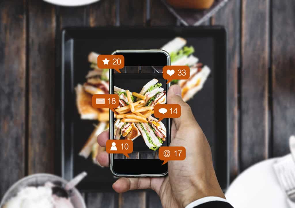 Taking food photograph by mobile smart phone, and sharing on social media, social network with notification icons