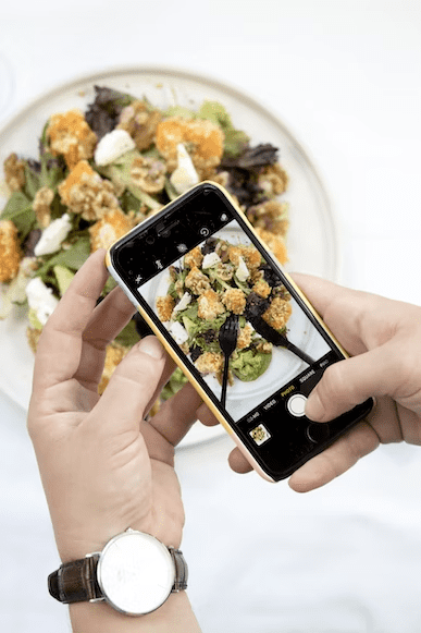 Person taking a picture of food at a restaurant.