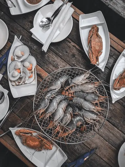Seafood (shrimps, fish, oysters) served on plates on a table.